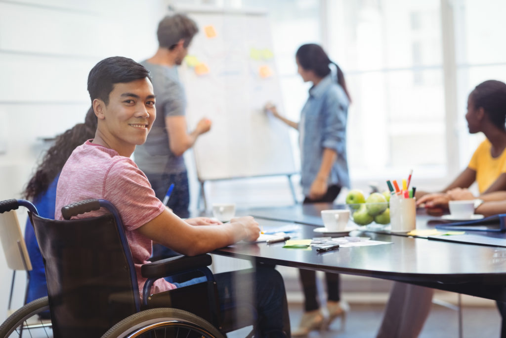 Portrait of happy business executive in a wheelchair attending a meeting at office